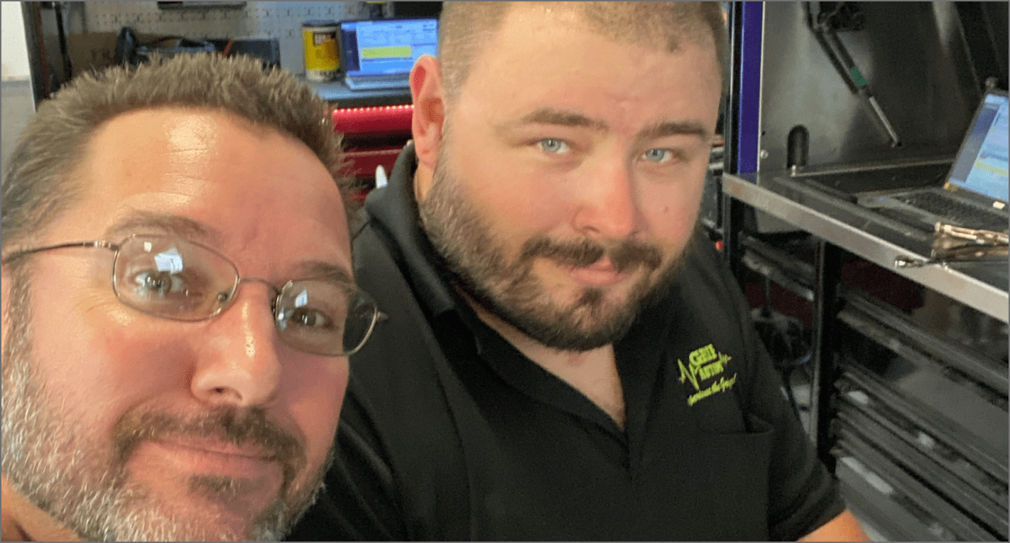 two of Griffis Automotive Repair team members taking a selfie in the shop bay area