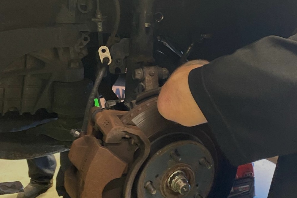 Shocks or Struts, Suspension Repair In Orlando, FL At Griffis Automotive Repair. Mechanic working on a vehicle suspension system for shocks or struts inside an auto repair shop.