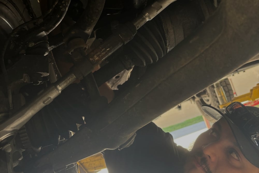 Shocks or Struts, Suspension Repair In Orlando, FL At Griffis Automotive Repair.. Mechanic inspecting and repairing a vehicle’s suspension system, focusing on shocks and struts, inside an auto repair shop.