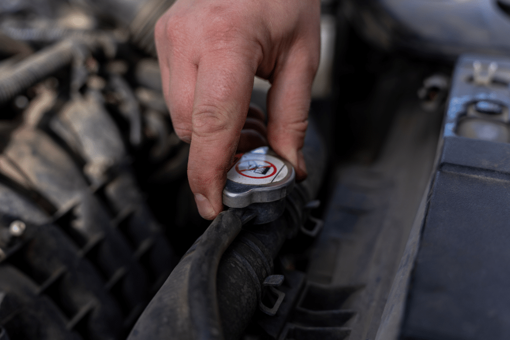 Cooling System Inspection in Orlando FL At Griffis Automotive Repair. Image Hand holding cooling system cap during vehicle cooling system inspection